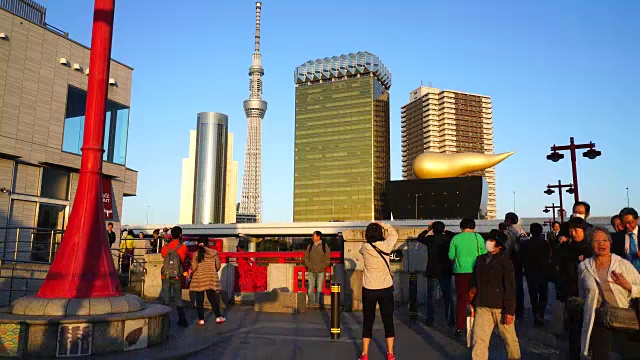 在东京浅草区安桥上，镜头捕捉到了夜间通勤者的身影。夕阳照亮了通勤者、东京天空树和市中心的城市景观。视频素材