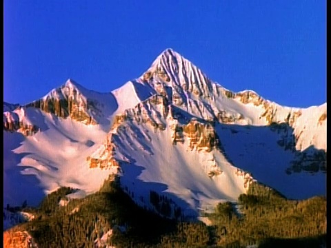 宽镜头时间流逝的阳光和阴影雪山与绿色的基地/落基山脉附近特柳赖德，科罗拉多州视频素材