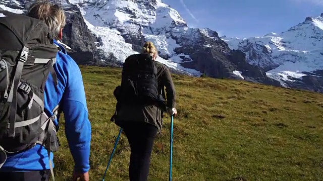 一对中年夫妇爬上山坡，走向冰封的山脉视频素材