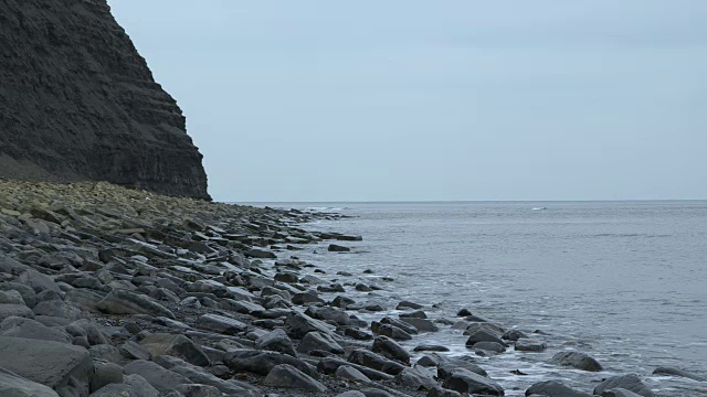 在多塞特长途汽车上，海浪翻滚在布满岩石的海滩上。视频素材