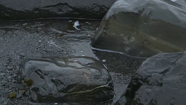 近距离拍摄的海浪滚过岩石上的海滩。视频素材