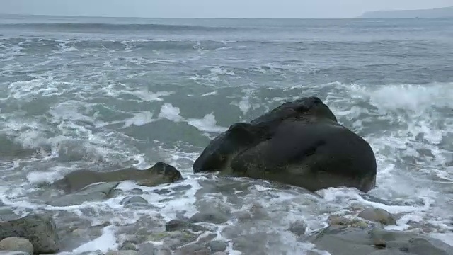 海浪冲击着多塞特海岸海滩上的一块大岩石。视频素材