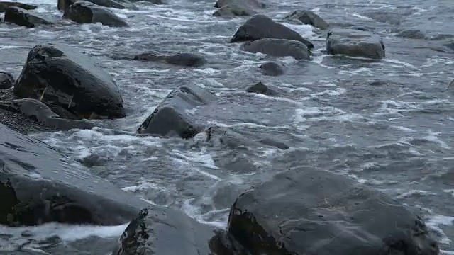 海浪在多塞特海滩的岩石上翻滚的近景。视频素材