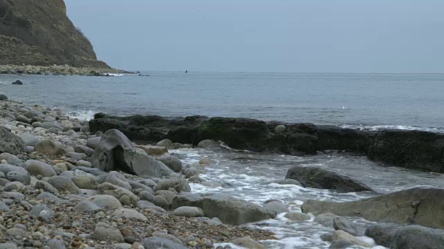 长镜头海浪翻滚到多塞特海岸的卵石滩上。视频素材