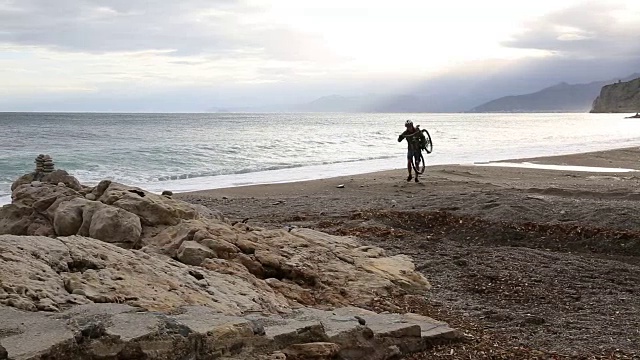 骑山地车的人沿着空荡荡的海滩，爬上石头台阶视频素材