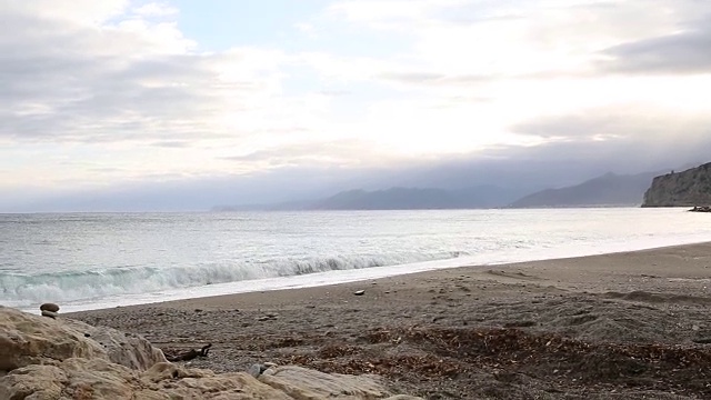 骑山地车的人来到空旷沙滩上的岩石堆前，眺望大海视频素材