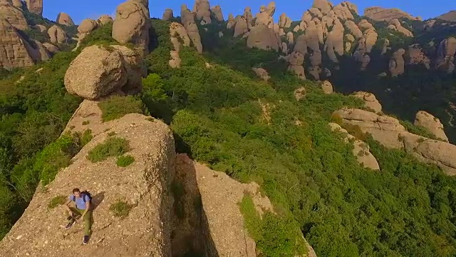 用无人机拍摄的航拍镜头，一个人在山顶沉思并拍摄蒙特塞拉特山脉的风景，他美丽而独特的构成在加泰罗尼亚地区。视频素材