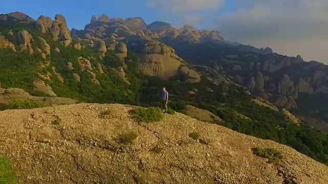 用无人机拍摄的航拍镜头，一个人在山顶沉思并拍摄蒙特塞拉特山脉的风景，他美丽而独特的构成在加泰罗尼亚地区。视频素材