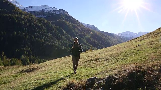 一名男性徒步旅行者朝着日出的方向走进了山上的草地视频素材