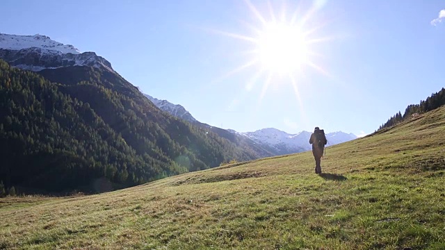 一名男性徒步旅行者朝着日出的方向走进了山上的草地视频素材