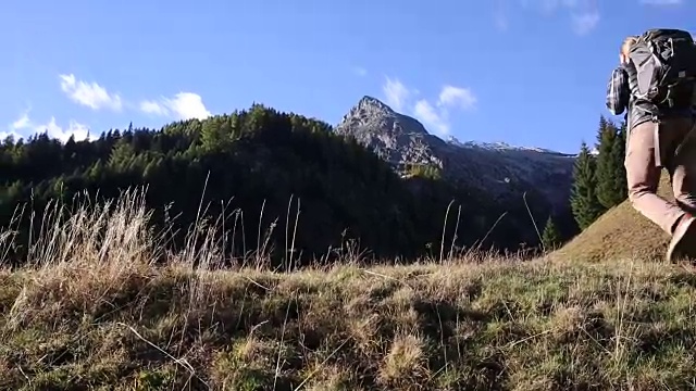 一名男性徒步旅行者朝着日出的方向走进了山上的草地视频素材