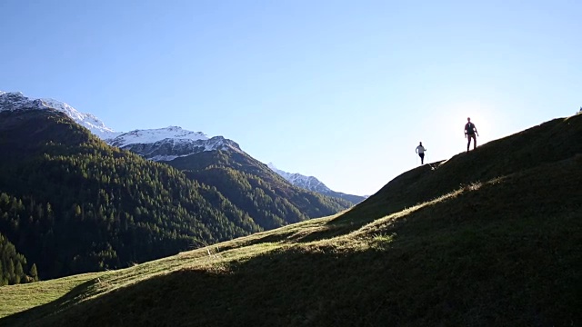 徒步旅行的情侣们沿着山脊上的草甸走着视频素材