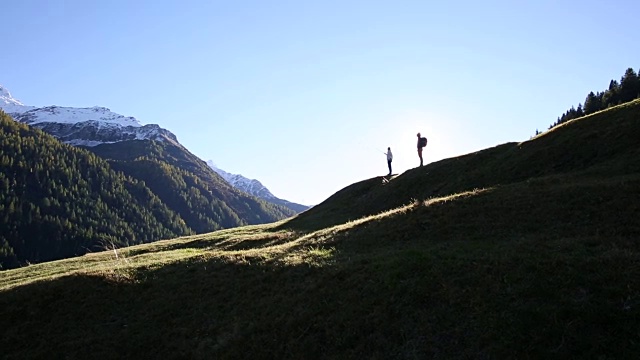 徒步旅行的情侣们沿着山脊上的草甸走着视频素材