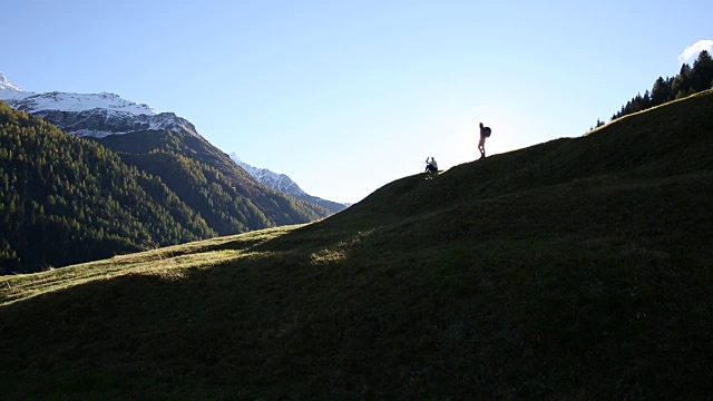 徒步旅行的情侣们沿着山脊上的草甸走着视频素材