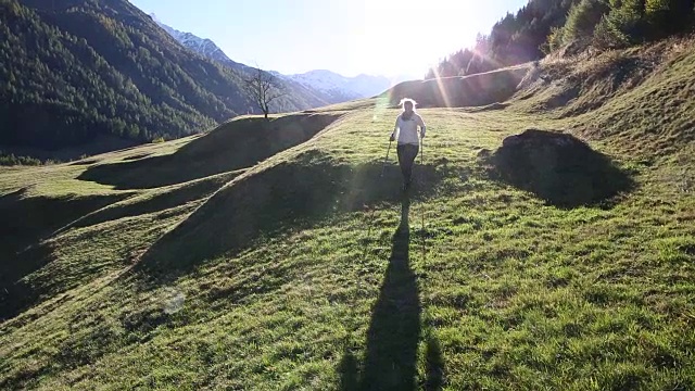 女人走进山中草地，迎着日出视频素材