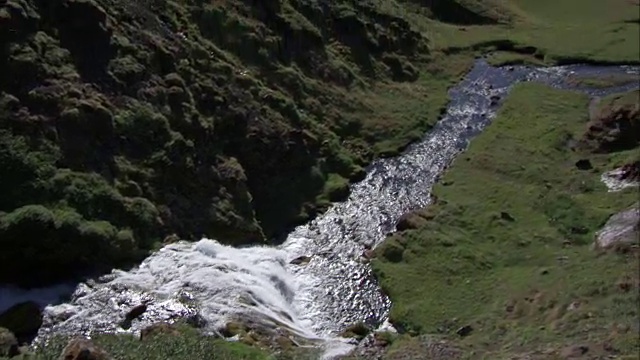 宽平移镜头的瀑布流下山谷和合并与湖泊与山的背景视频素材