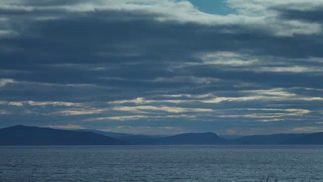 在湖泊和山脉上滚动的云的延时宽镜头视频素材