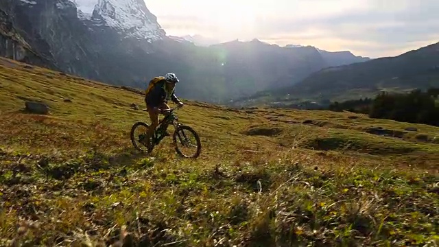 一名中年男子骑自行车穿过山区草地视频素材