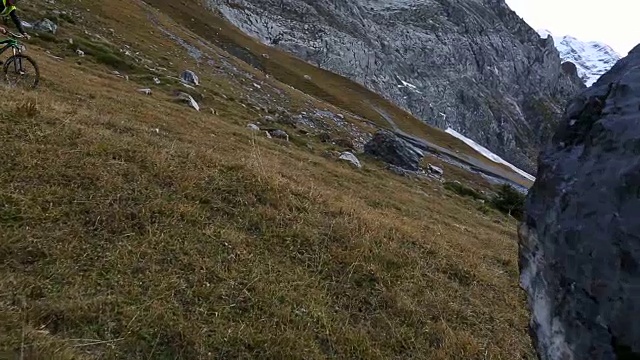 一名中年男子骑自行车穿过山区草地视频素材