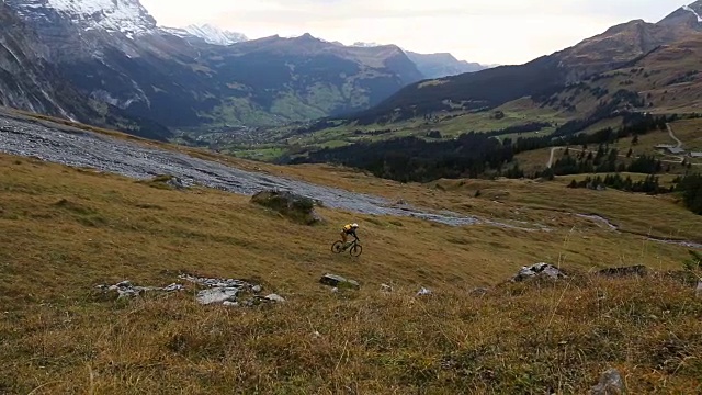 一名中年男子骑自行车穿过山区草地视频素材