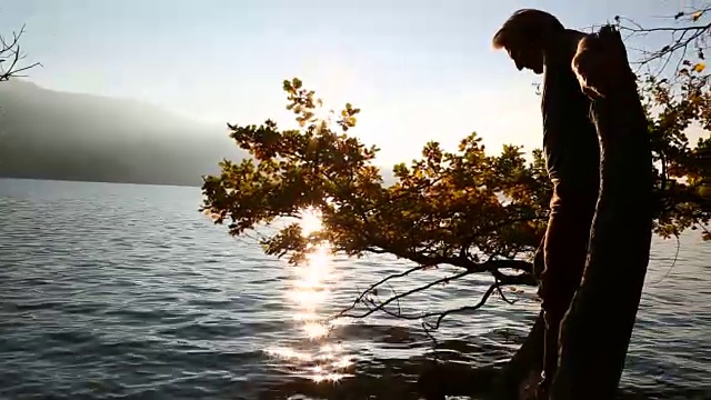 一位中年男子走在树干上越过山湖视频素材