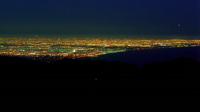 高角度广角拍摄时间推移车下山与洛杉矶的灯光在背景/黄昏到夜晚/加利福尼亚视频素材