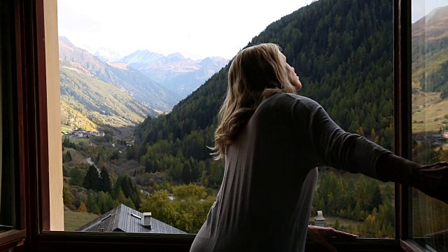 女人打开百叶窗，看外面的山景视频素材