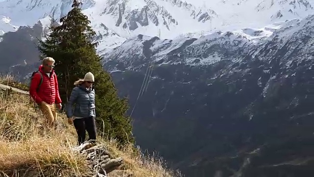 徒步夫妇沿着小路穿过山坡，雪山视频素材