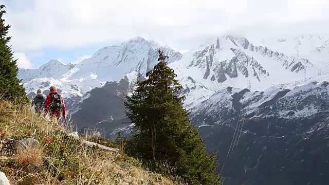 徒步夫妇沿着小路穿过山坡，雪山视频素材