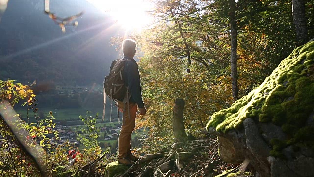 一名男性徒步旅行者走过山村上方的秋日森林视频素材