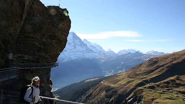 女性徒步旅行者沿着山坡上有守卫的小路行走视频素材