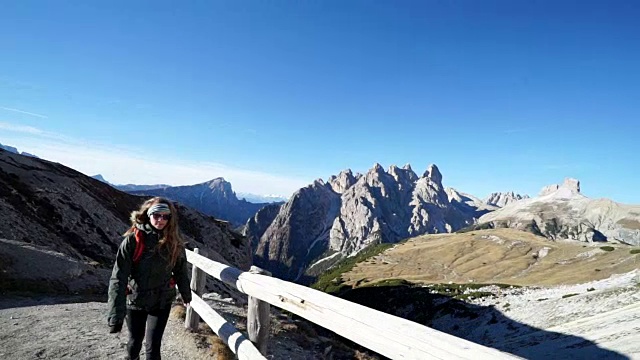 女性徒步旅行者攀登小路与岩石山脉在远处视频素材