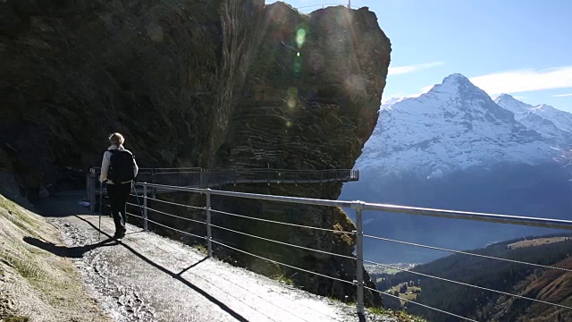 女性徒步旅行者沿着山坡上有守卫的小路行走视频素材