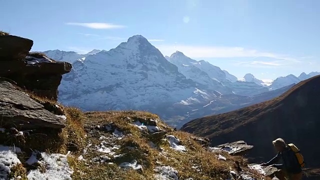 男性徒步旅行者攀登草地和雪山之上的山脊视频素材