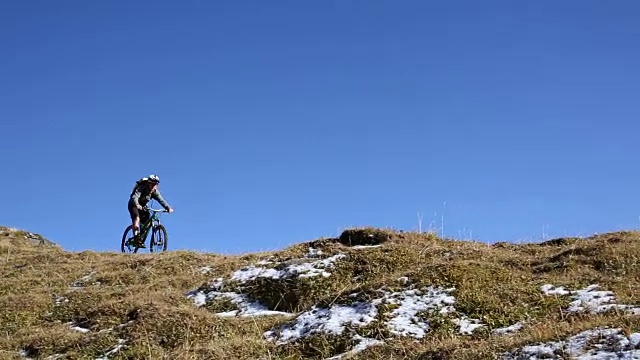 山地自行车下山的草地和雪山之上的山脊视频素材