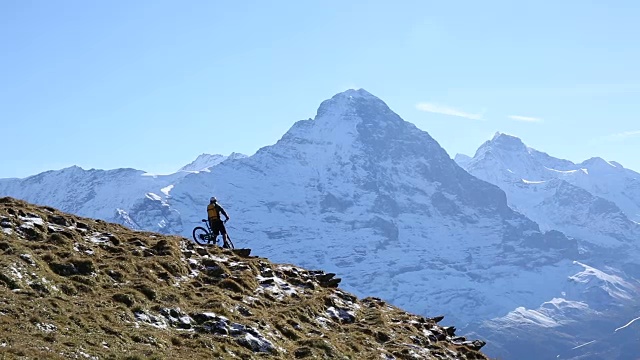 山地自行车下山的草地和雪山之上的山脊视频素材