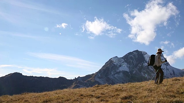 女性徒步旅行者攀登草地，雪山盖顶视频素材