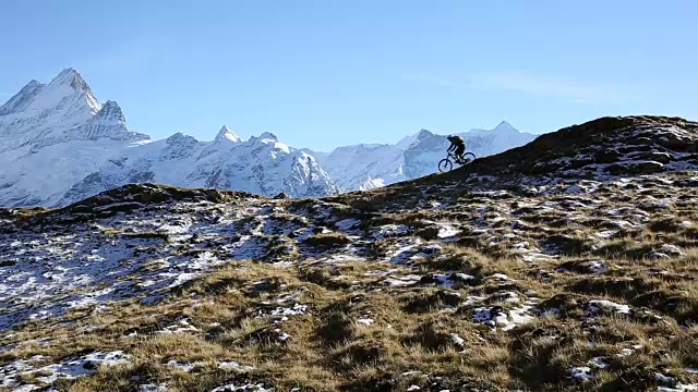 山地车从草地和雪山上下来视频素材