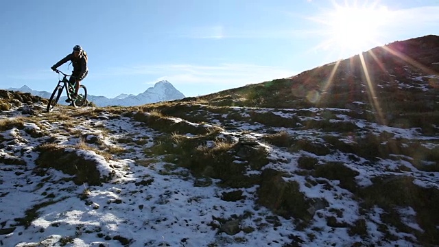 山地车从草地和雪山上下来视频素材