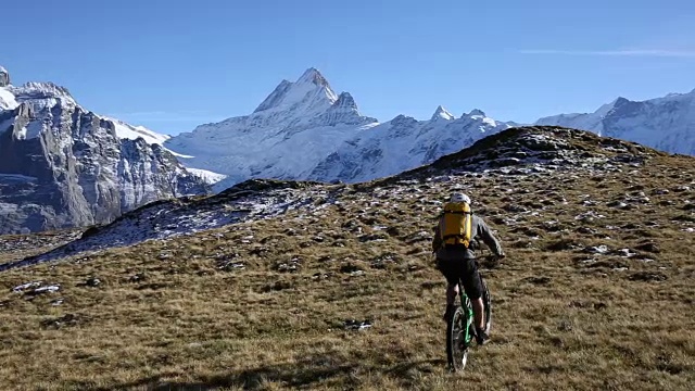 山地自行车攀登草地和雪岭，雪山视频素材