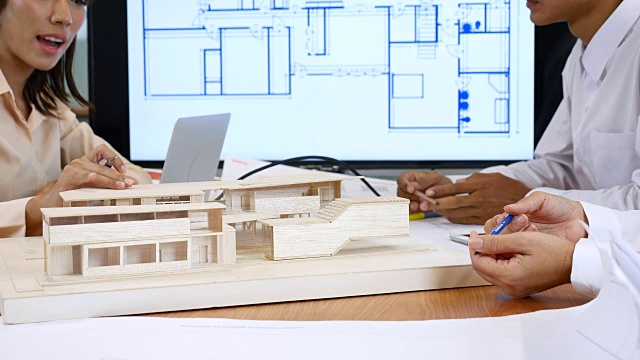 近距离的建筑师手会议与蓝图显示屏幕和人工模型视频素材