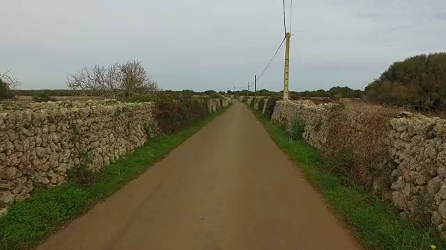 无人机在美丽的梅诺卡岛乡村上空拍摄的航拍镜头，汽车在田野和漂亮的石墙之间行驶。4 k UHD。视频素材