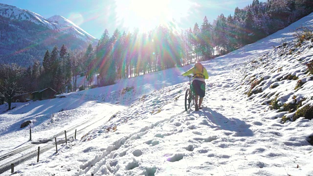 年轻人把山地车推到雪地上视频素材