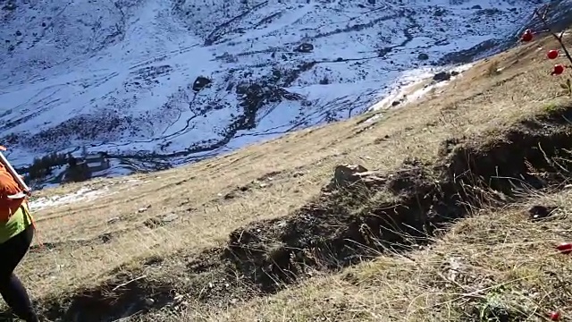 女性徒步者沿着山坡下山，身后是雪峰视频素材