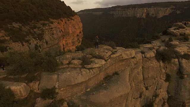 一名男子在周末徒步旅行期间，从一个令人惊叹的岩石视角拍摄日落和加泰罗尼亚地区令人惊叹的悬崖景观，无人机拍摄的航拍镜头。视频素材