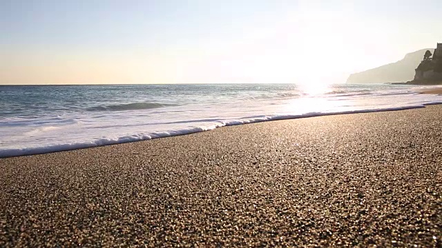 日出时，海浪拍打着空旷的海滩视频素材