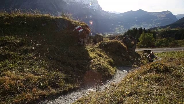 女性徒步旅行者沿着山间草地的小路行走视频素材