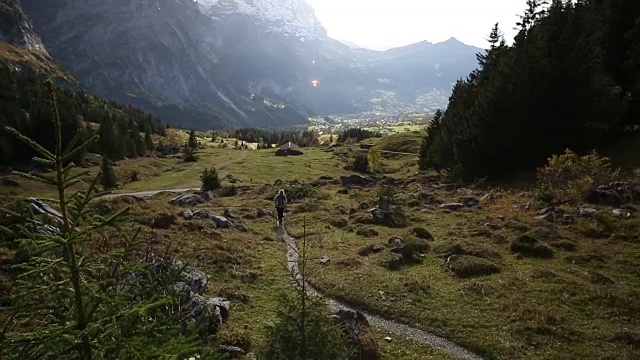 女性徒步旅行者沿着山间草地的小路行走视频素材