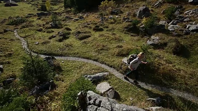 女性徒步旅行者沿着山间草地的小路行走视频素材