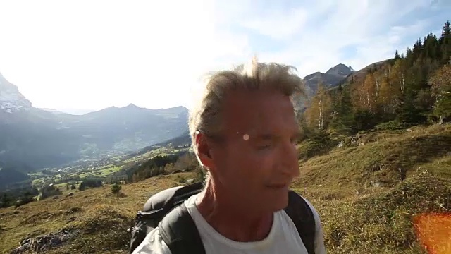 男性徒步旅行者沿着山间草地的小路行走视频素材